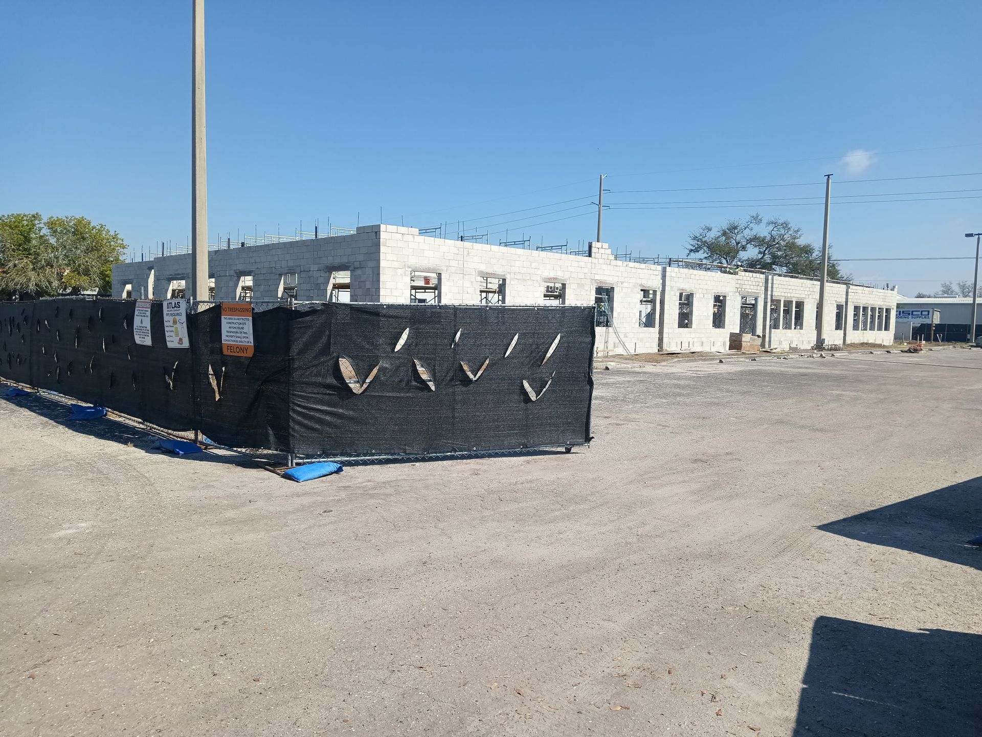 Building under construction behind a black construction fence on a gravel lot.