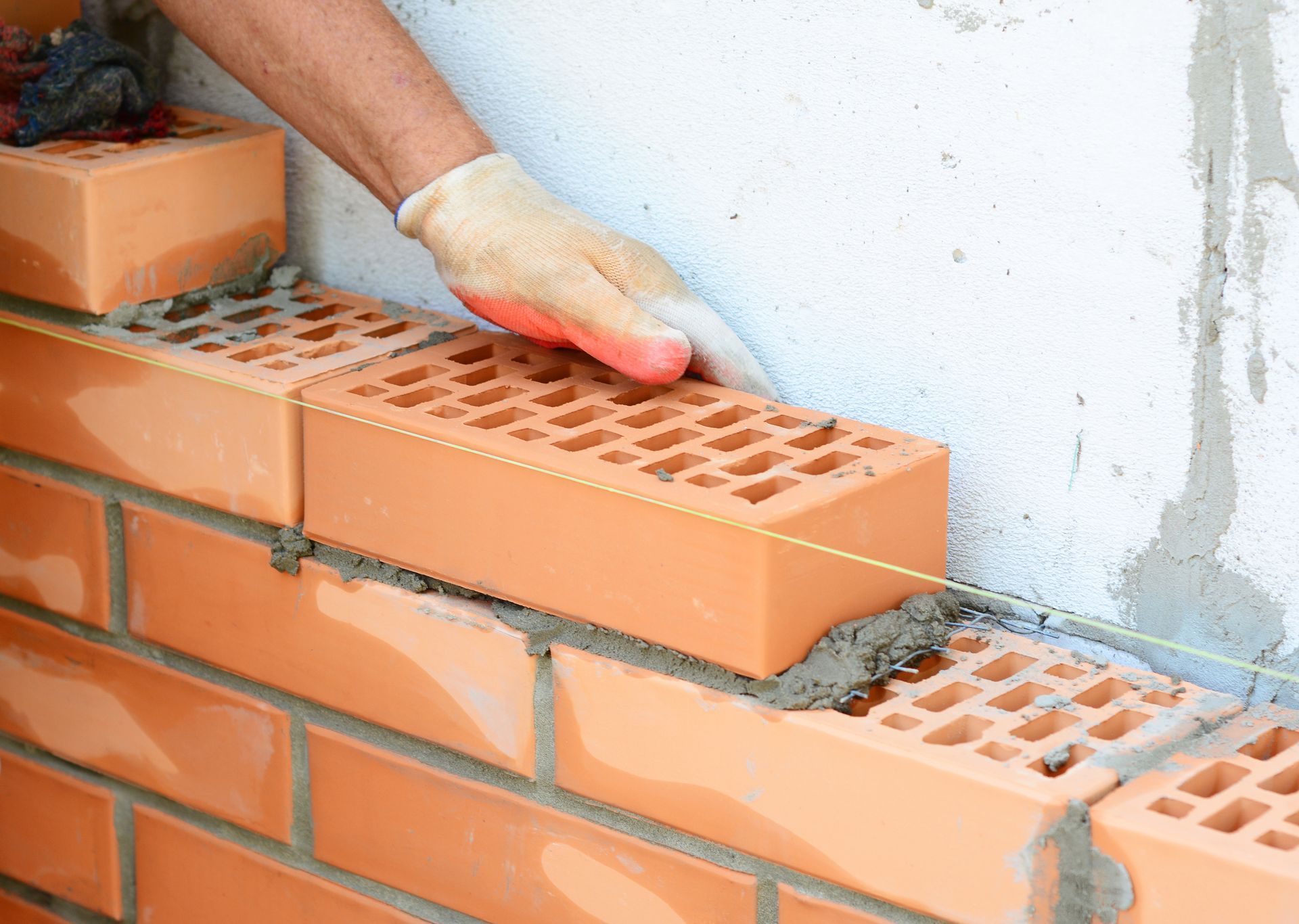 Close-up of a residential masonry contractor applying mortar to a brick using a trowel.