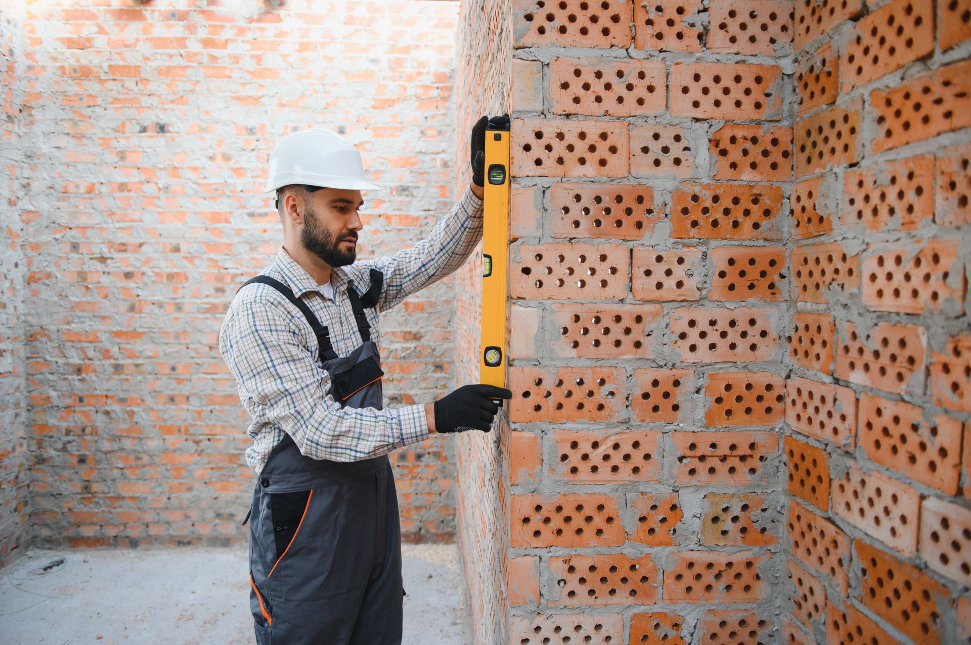 Construction worker using a spirit level on a brick wall.