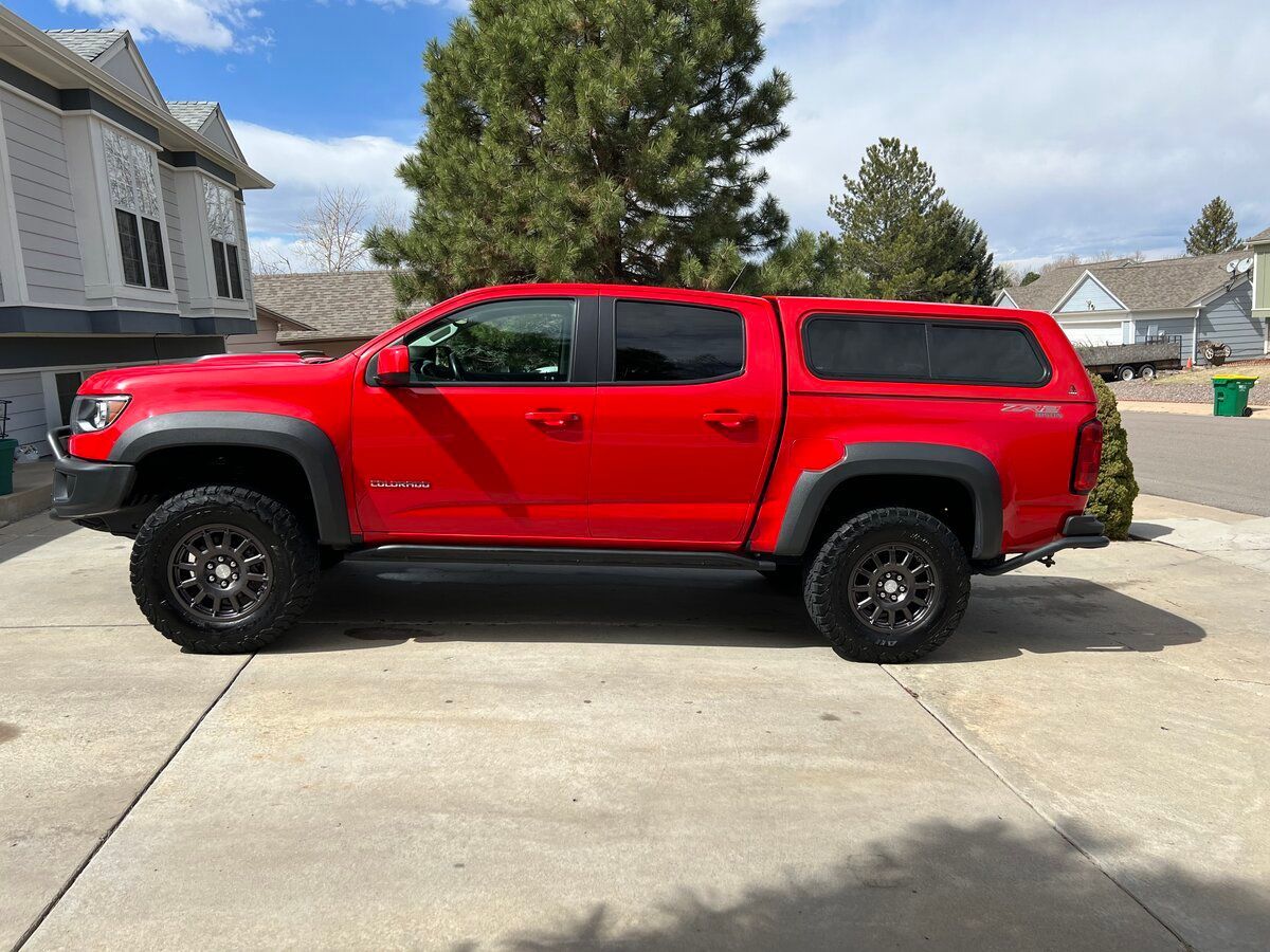 A red truck is parked in a driveway in front of a house.