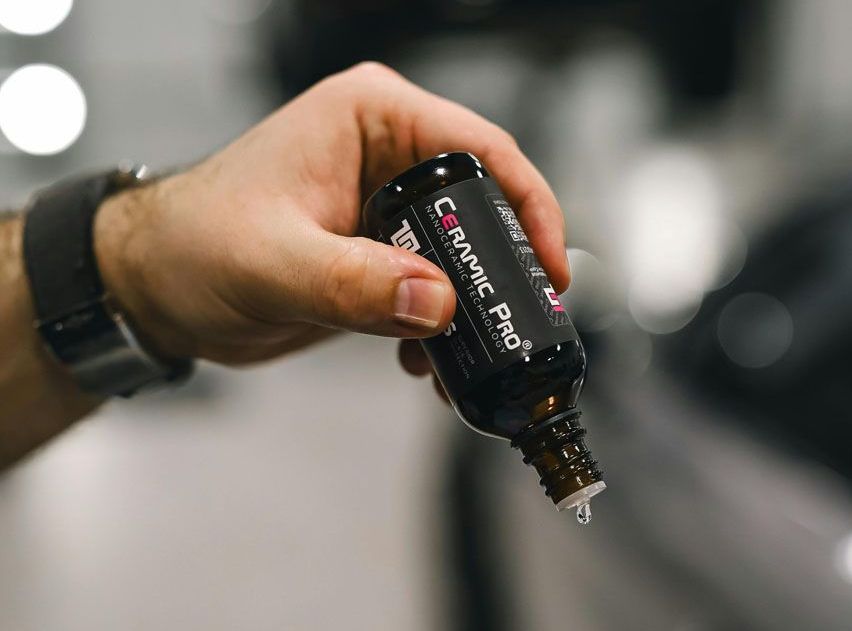 A person is holding a bottle of ceramic pro in their hand.