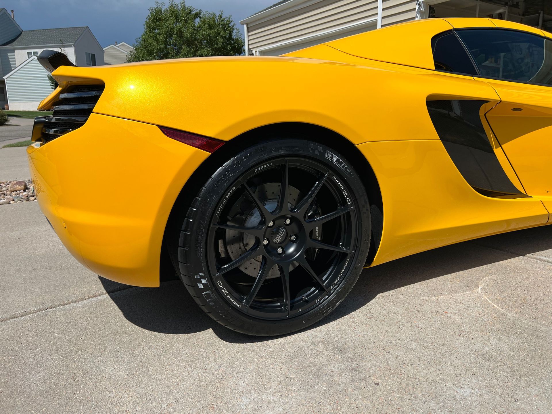 A yellow sports car with black wheels is parked on the side of the road.