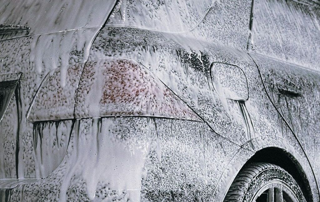 A black and white photo of a car covered in foam.