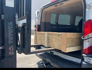 A toyota van with a forklift attached to the back of it.