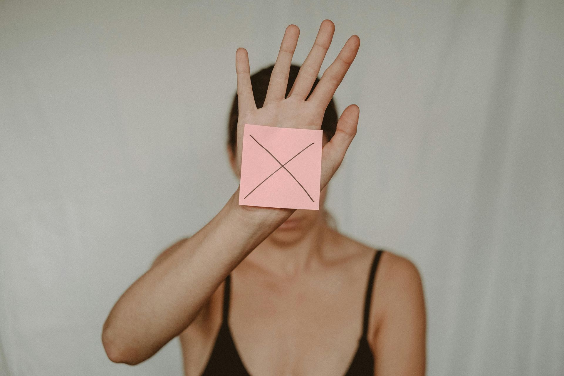 roze geeltje met een kruis erop in de rechterhand van een vrouw