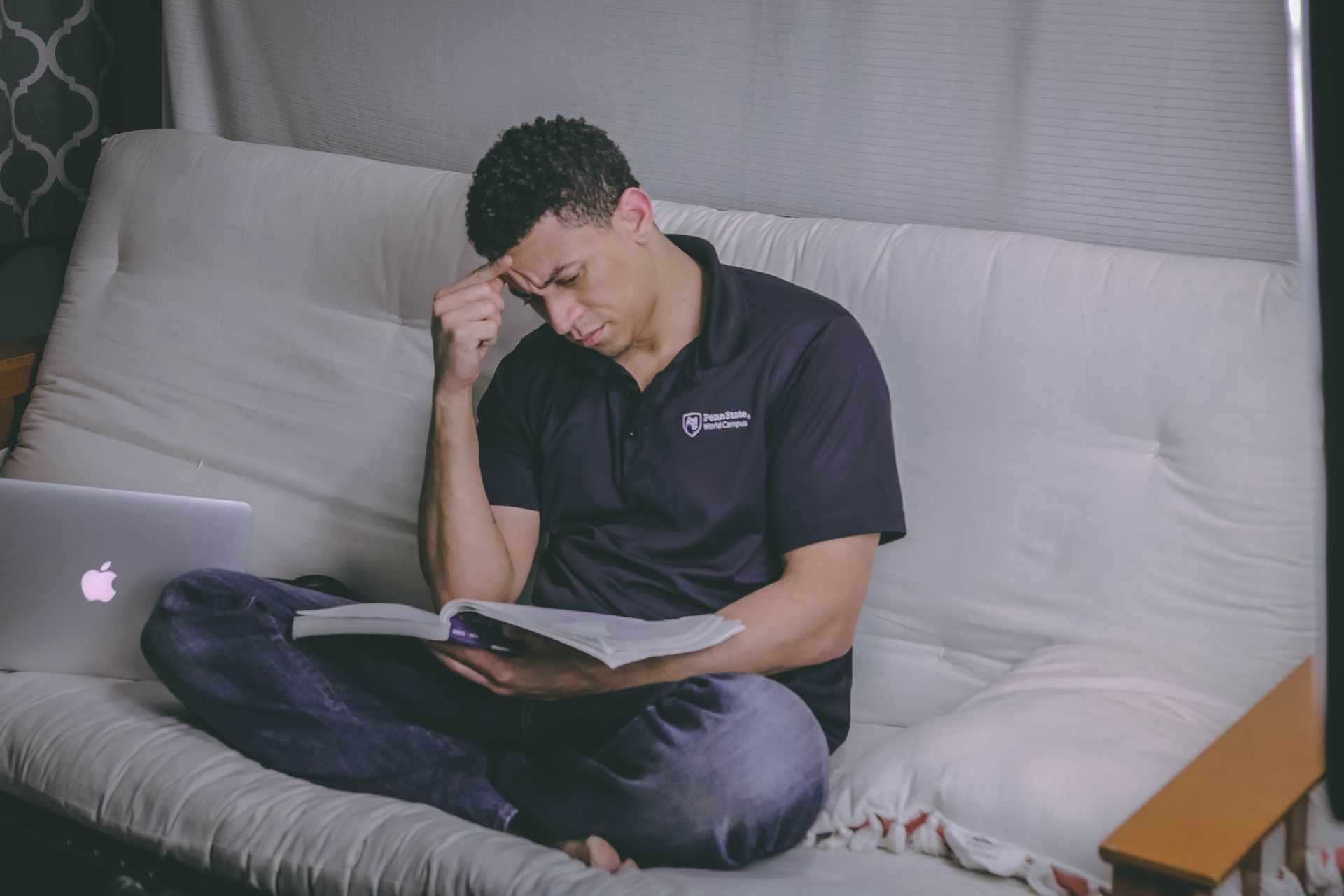 Man die in kleermakerszit aan het studeren is op de bank