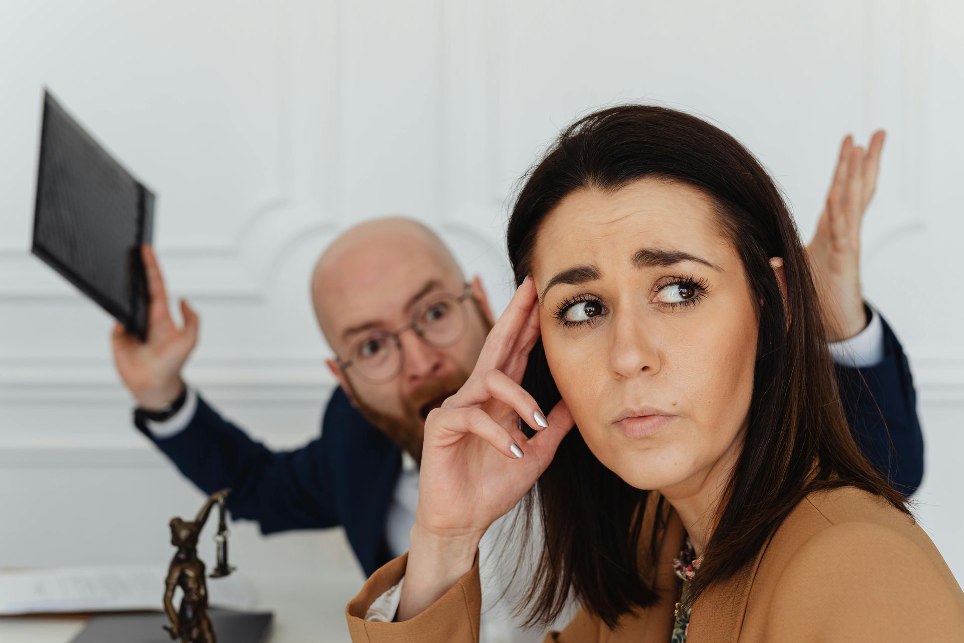 Boze man op de achtergrond met document in zijn rechterhand en een verdrietige vrouw op de voorgrond