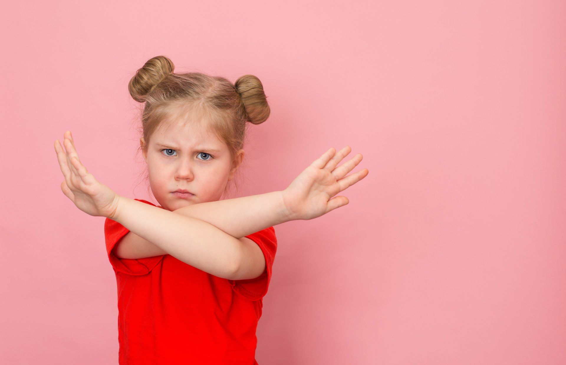 meisje in rood jurkje maakt met haar gekruiste armen een afwijzende beweging
