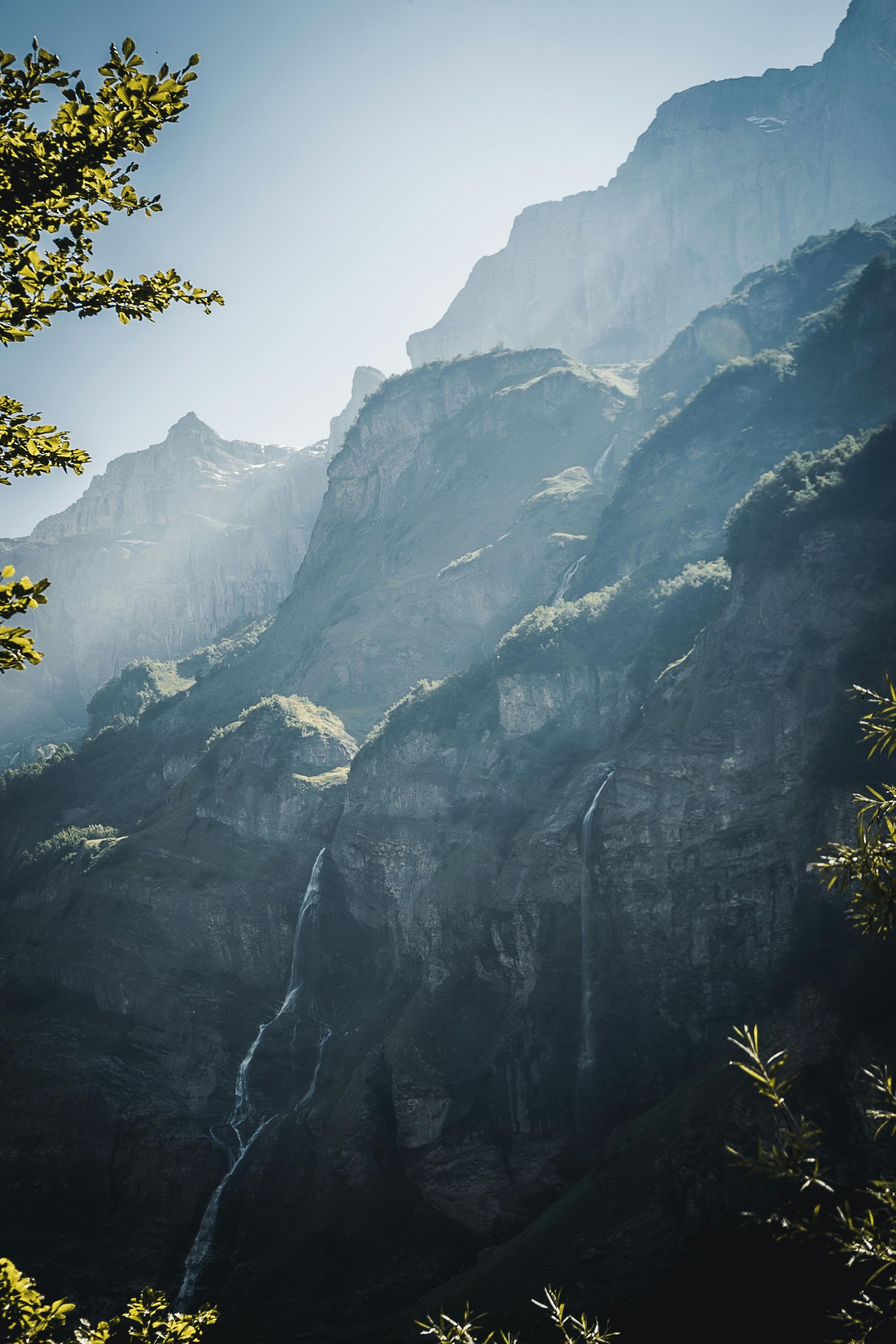 Sunlit mountain range with a waterfall cascading down a rocky cliff. Resembles structures on how to navigate anxiety from ADHD symptoms.