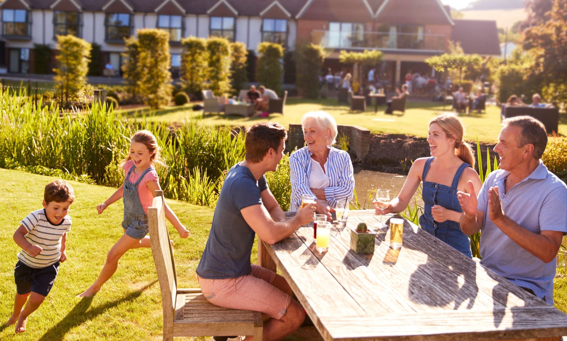 People enjoying drinks and conversation at a sunny picnic table in a garden courtyard