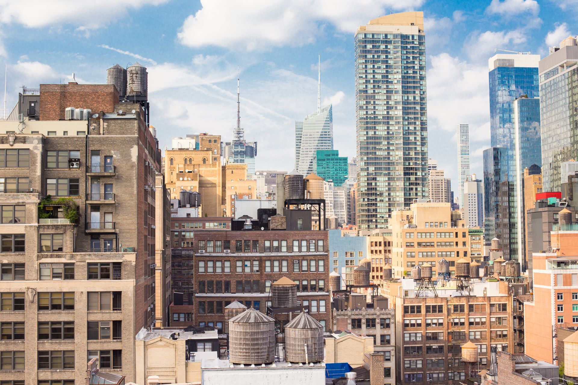 City skyline with tall office buildings under a partly cloudy blue sky.