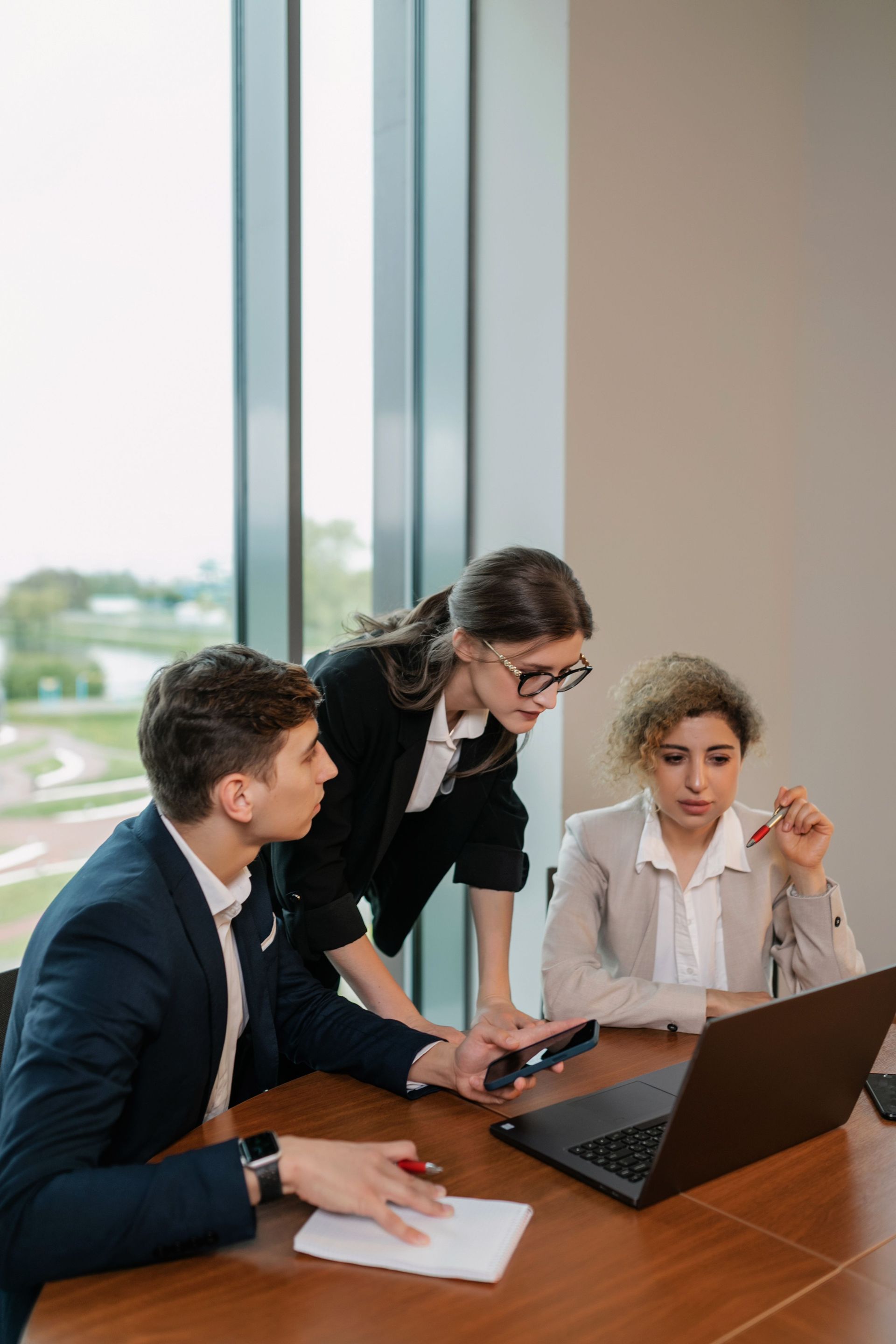 Business meeting with laptop, tablet, and a small house model on a wooden table