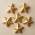 Six gold star decorations arranged on a beige surface.