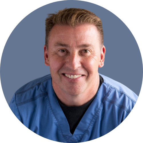 A man in a blue scrub is smiling for the camera