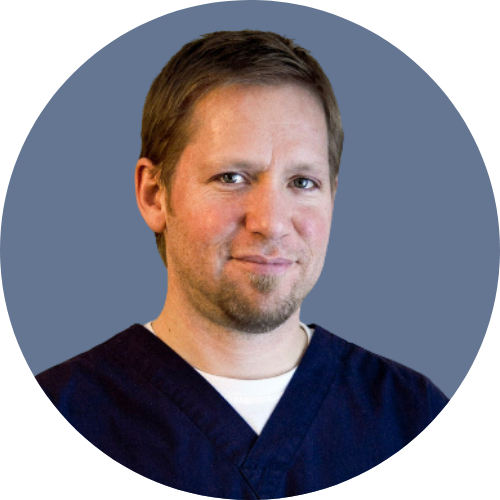 A man with a beard is wearing a blue scrub top