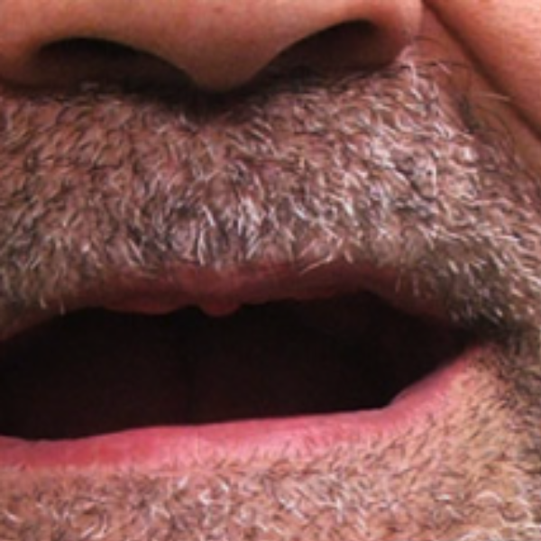 A close up of a man 's mouth with a beard
