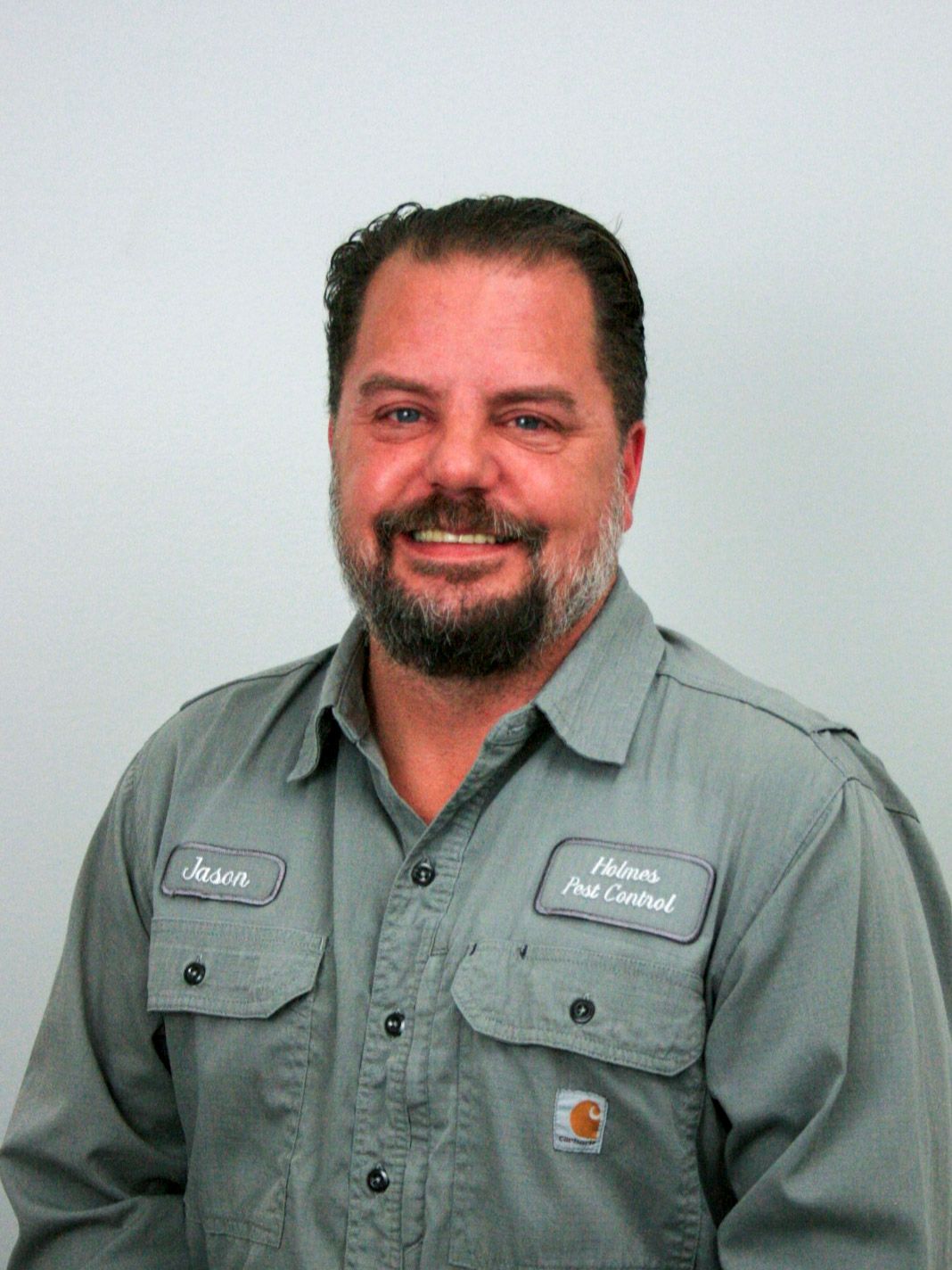 Man with a beard in a gray work shirt, with name badge that says
