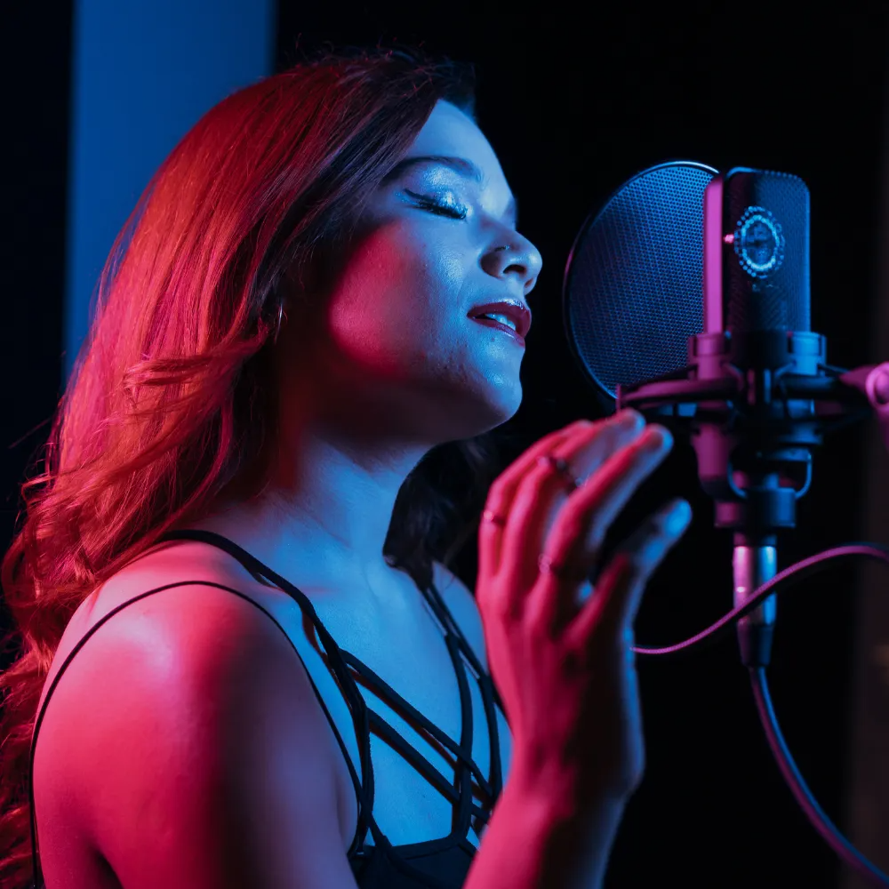 Singer recording in a studio under red and blue lighting, singing into a microphone