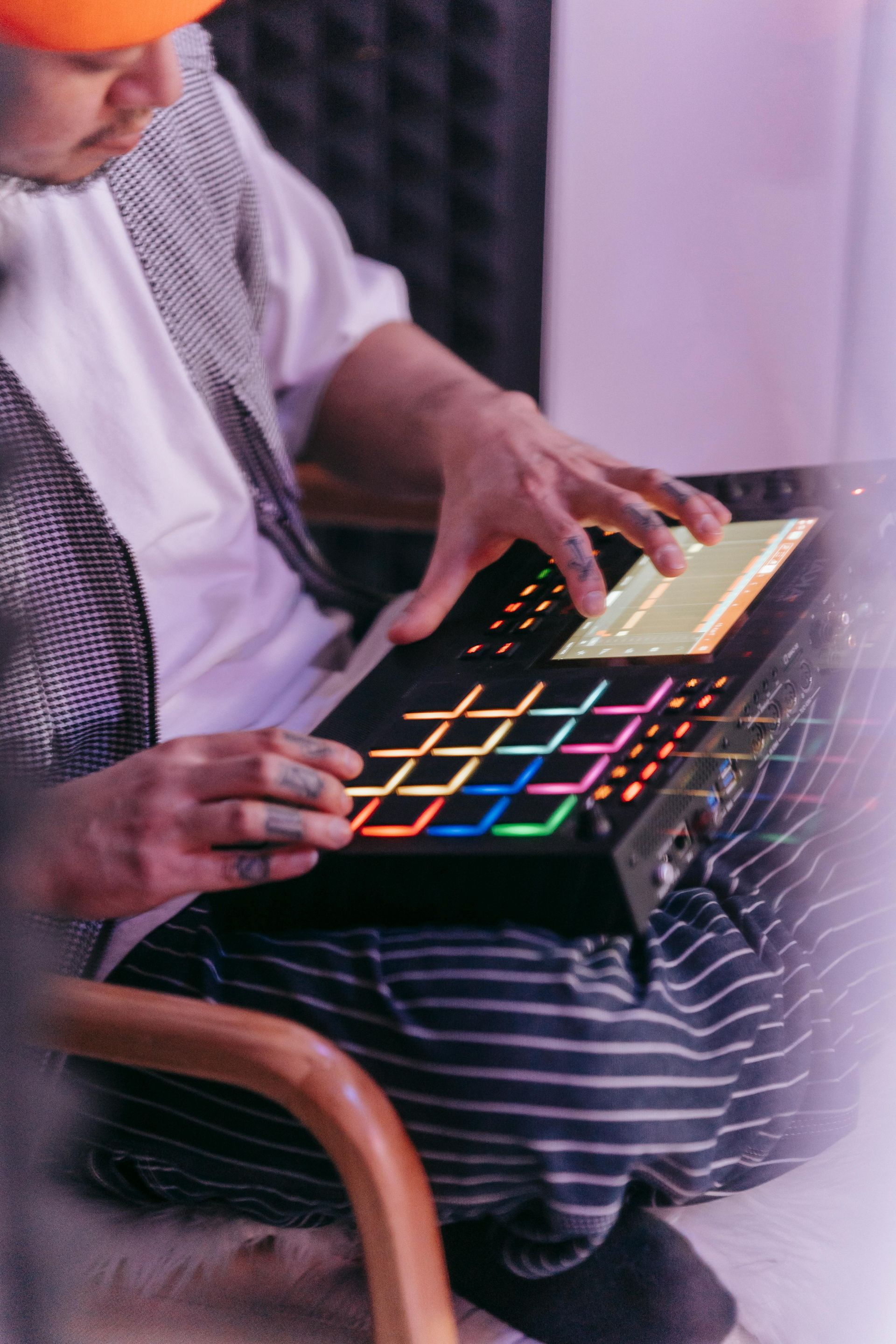 Person using a colorful music pad controller on their lap while seated indoors