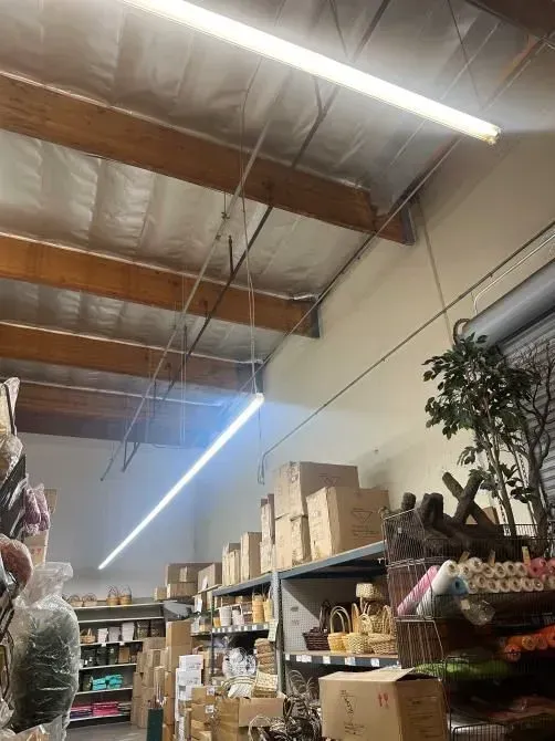 Warehouse store aisle with shelves of boxed goods and hanging items under exposed ceiling beams