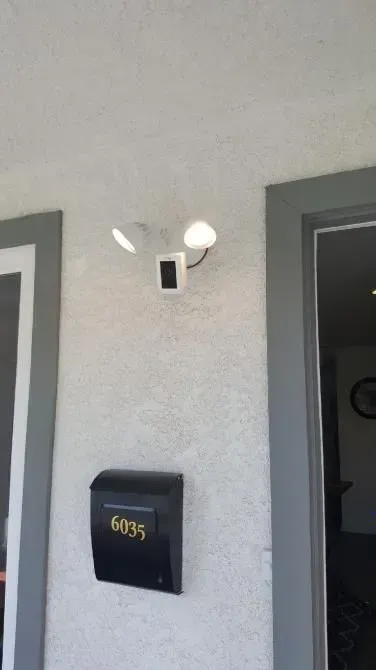Apartment door with black mailbox and wall light above, next to a doorway.