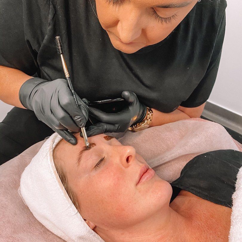 A woman is laying on a bed getting her eyebrows painted - Beauty & Laser by Sarah in Long Jetty, NSW