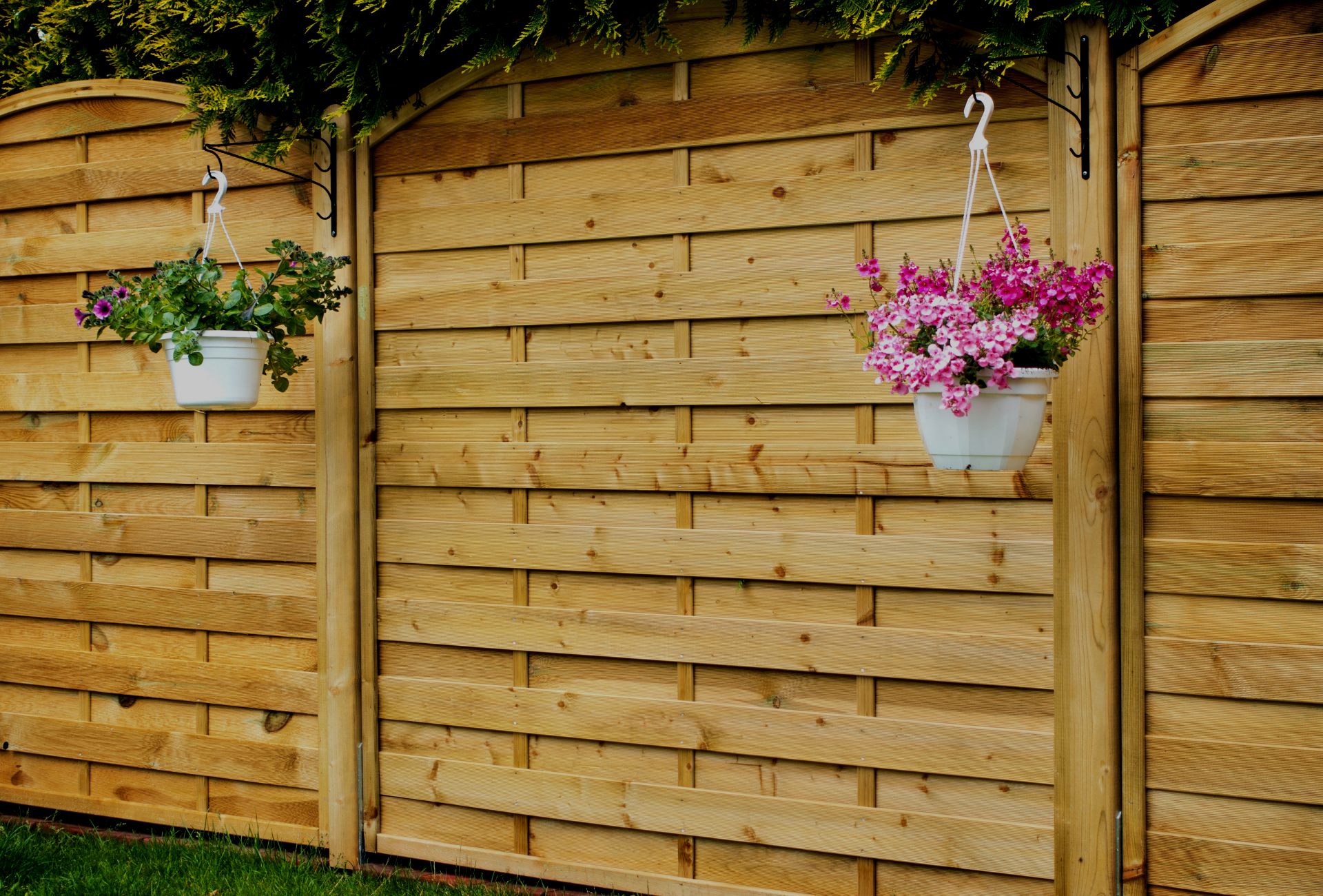 A wooden fence with hanging baskets of flowers on it.