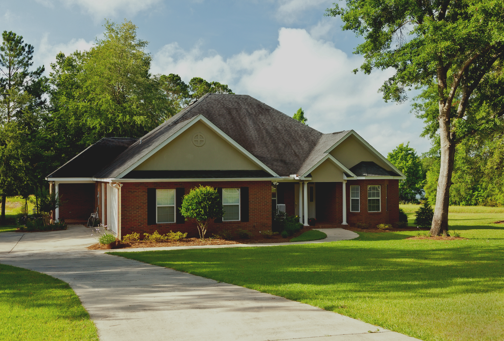 A brick house with a driveway leading to it