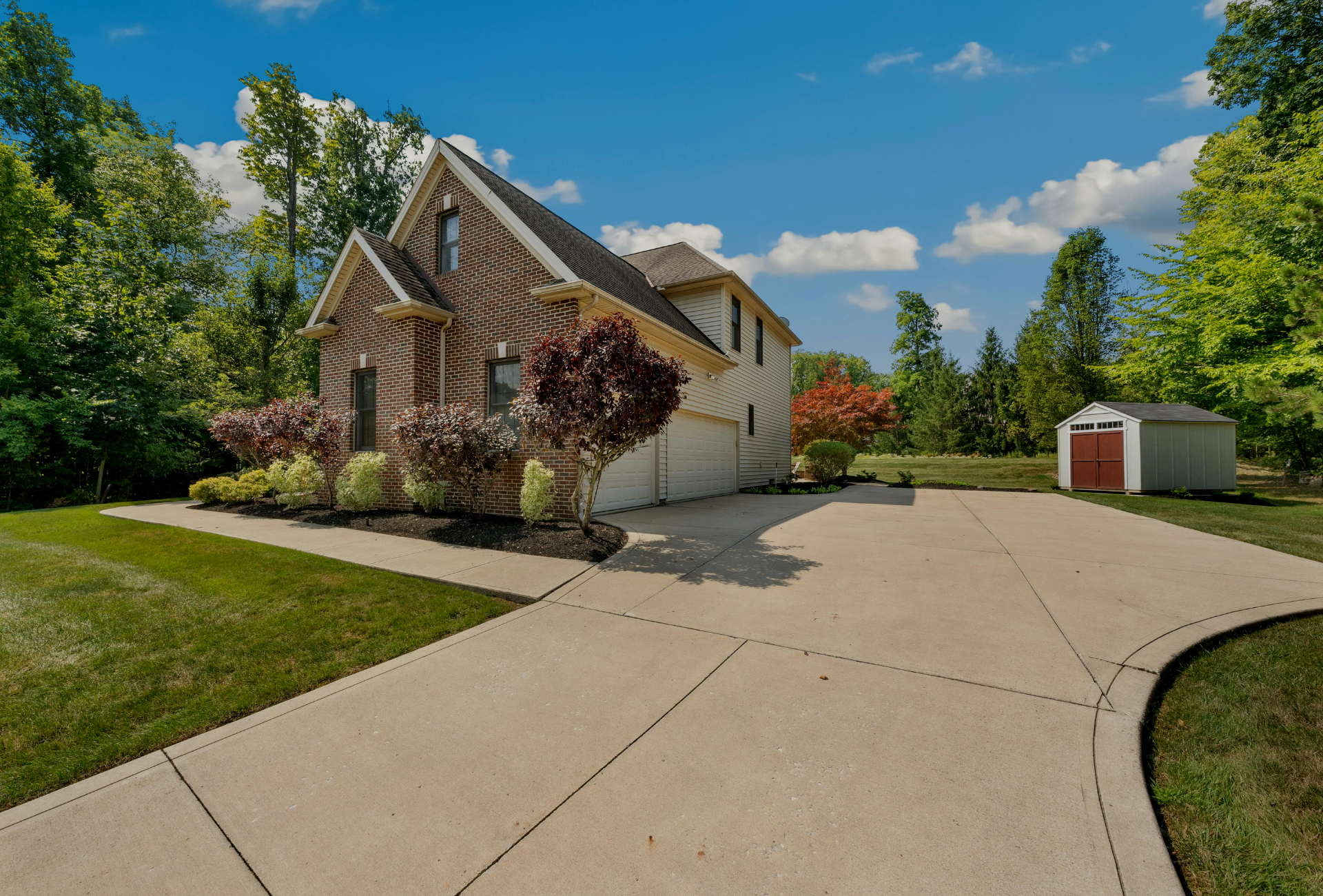 A large brick house with a large driveway leading to it.