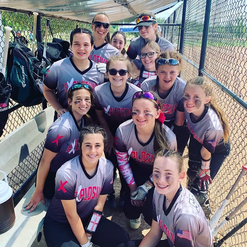 Explosive Fastpitch softball team in a dugout.