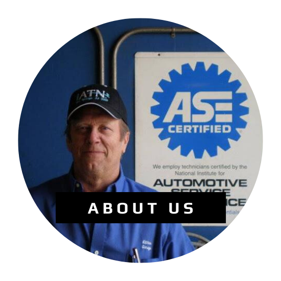 A person in a blue shirt and hat standing in front of an ASE Certified sign for an 