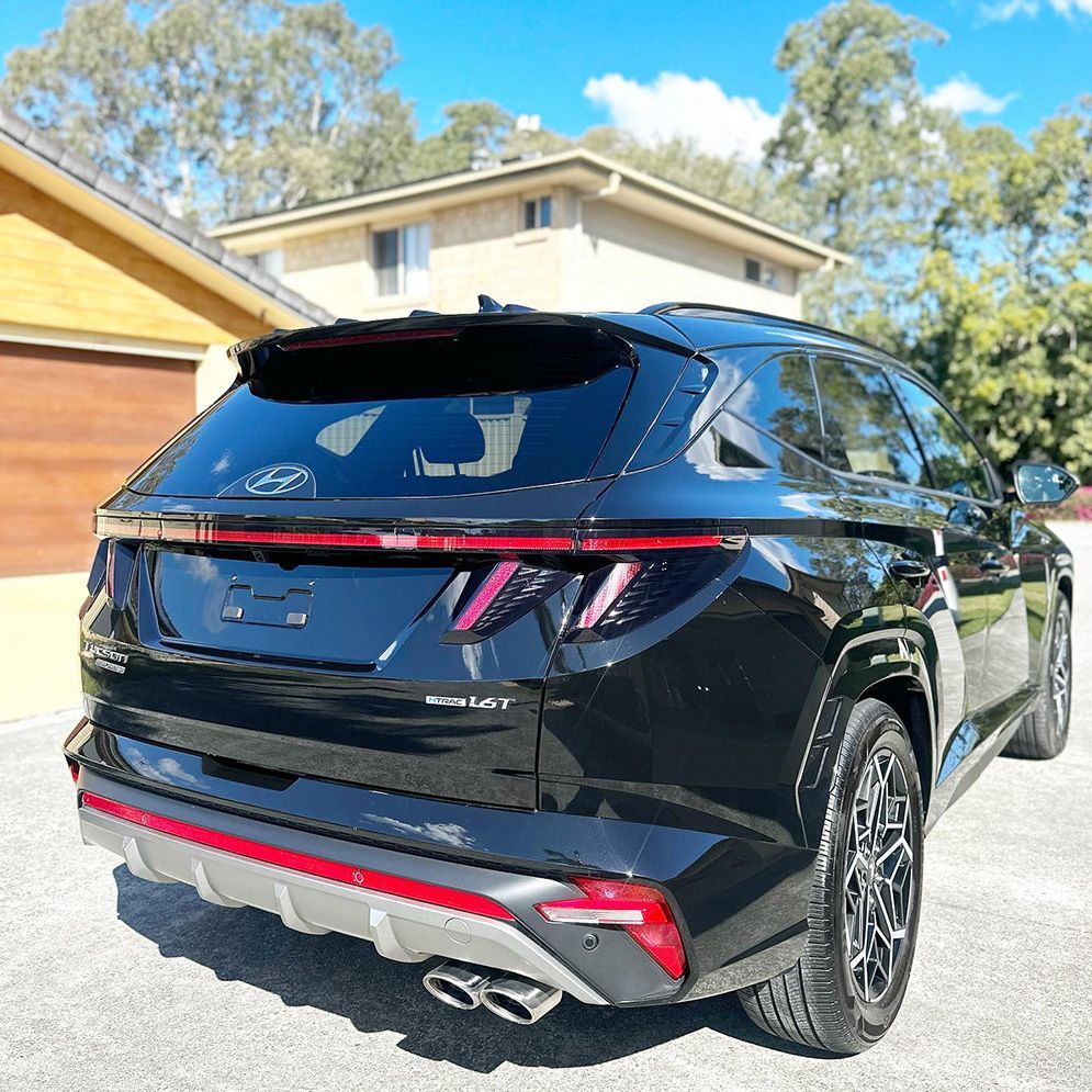 Black SUV parked in a driveway, rear three-quarter view with red taillights and chrome accents — Remedy Mobile Car Detailing in Gold Coast, QLD