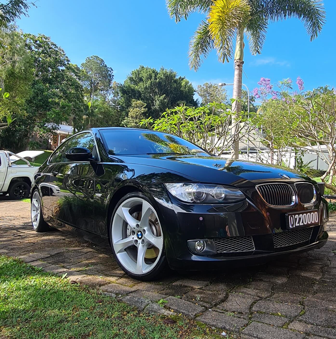 Black BMW sedan parked on a stone driveway in a sunny tropical yard — Remedy Mobile Car Detailing in Gold Coast, QLD