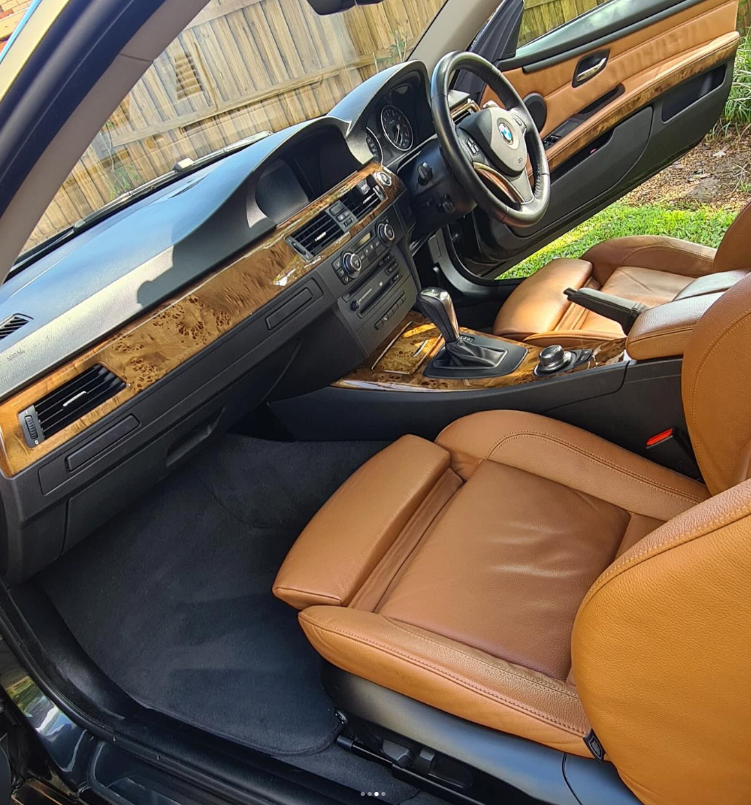 Luxury car interior with tan leather seats, wood dashboard trim, and black floor mats, viewed from the passenger side — Remedy Mobile Car Detailing in Gold Coast, QLD