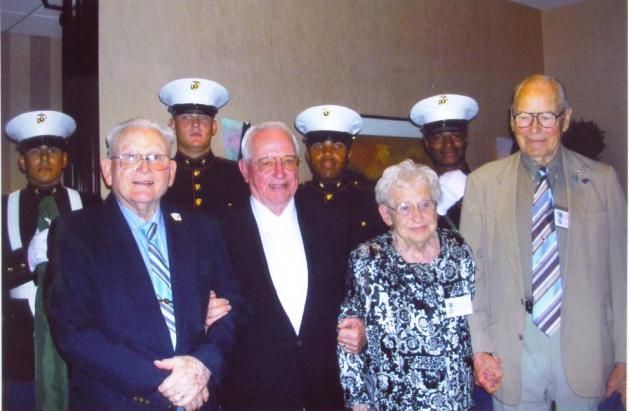 Veterans in formal attire with military honor guard, indoors.