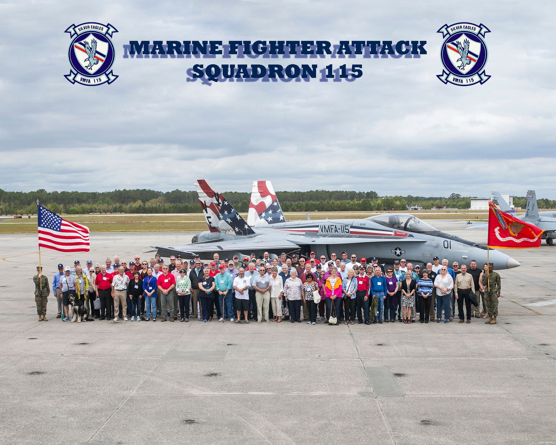Marine Fighter Attack Squadron 145 group photo in front of a jet on an airfield, U.S. flag visible, cloudy sky.