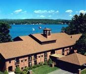 Brick building with brown roof by a blue lake under a clear sky.
