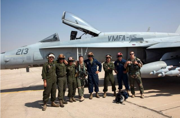 Group of Marines pose with a jet, the words