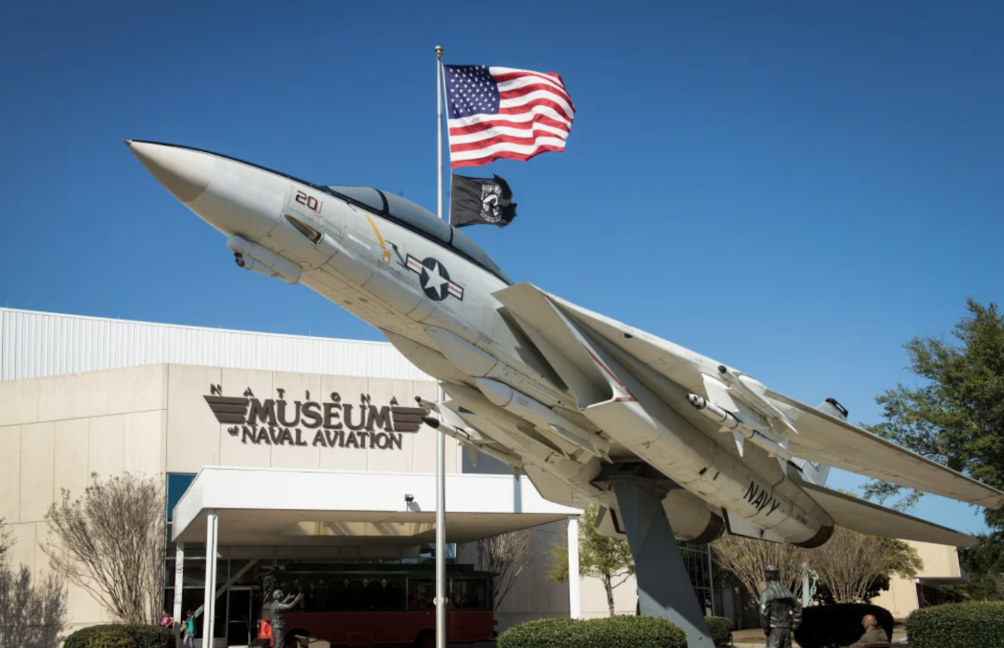 F-14 Tomcat jet on display in front of the National Naval Aviation Museum building with American flag.