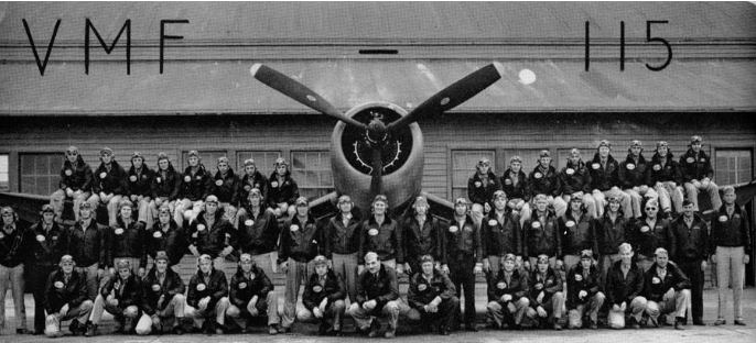 Group portrait of a military squadron (VMF-115) in front of an aircraft; black and white photograph.