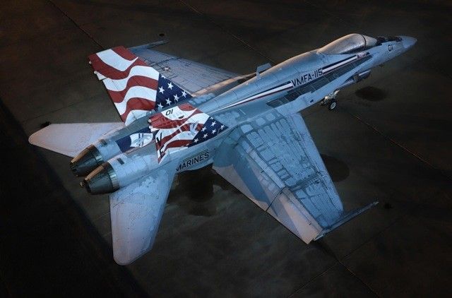 F/A-18 fighter jet with American flag tail art, parked on a dark surface.