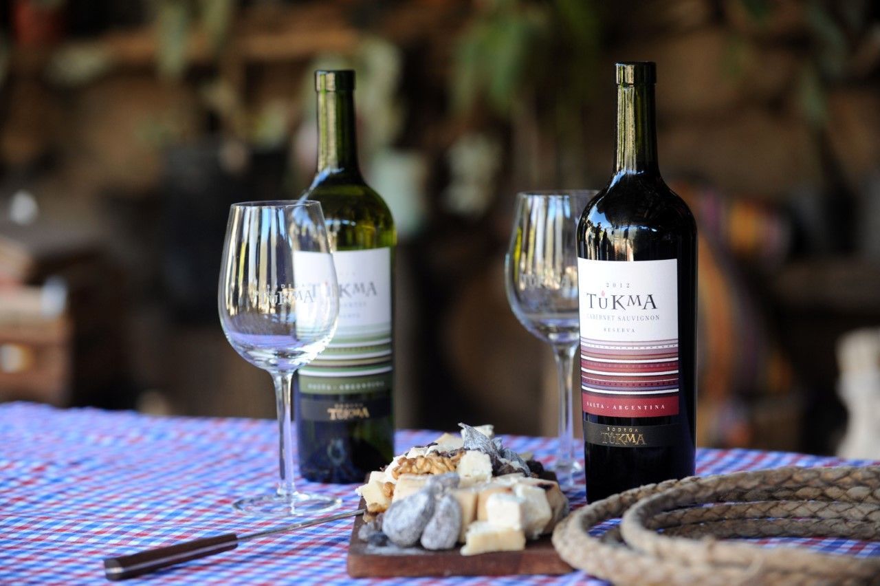 Sobre una mesa hay dos botellas de vino y dos copas de vino.