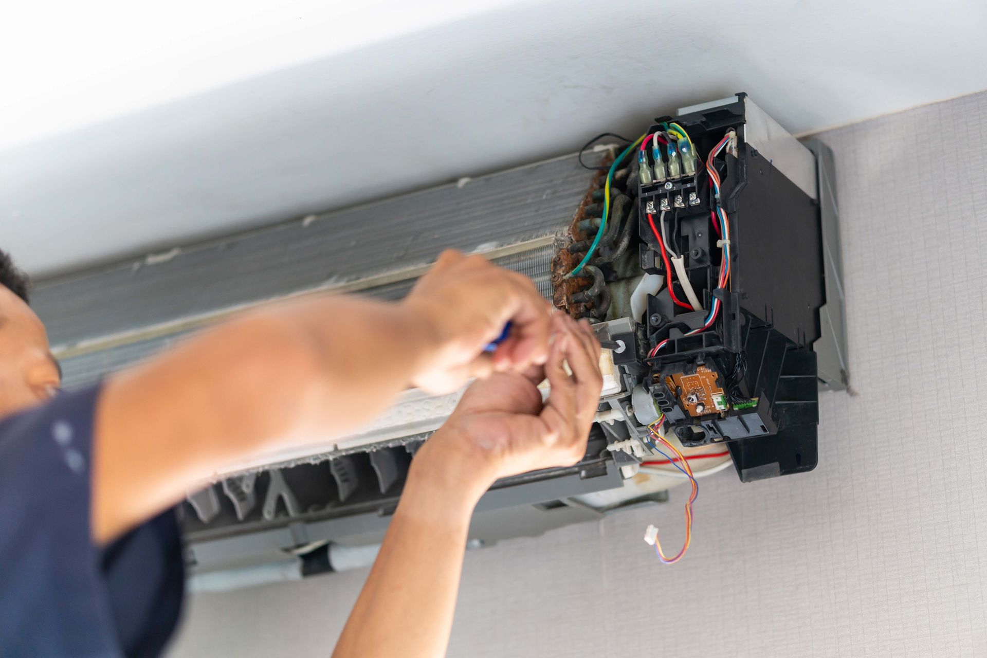 Technician wiring an open electrical panel mounted near the ceiling Technician wiring an open electrical panel mounted near the ceiling
