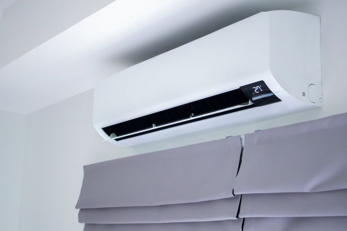 Air-Conditioning Services — Memphis, TN — Absolute Comfort White wall-mounted air conditioner unit above gray window shade.