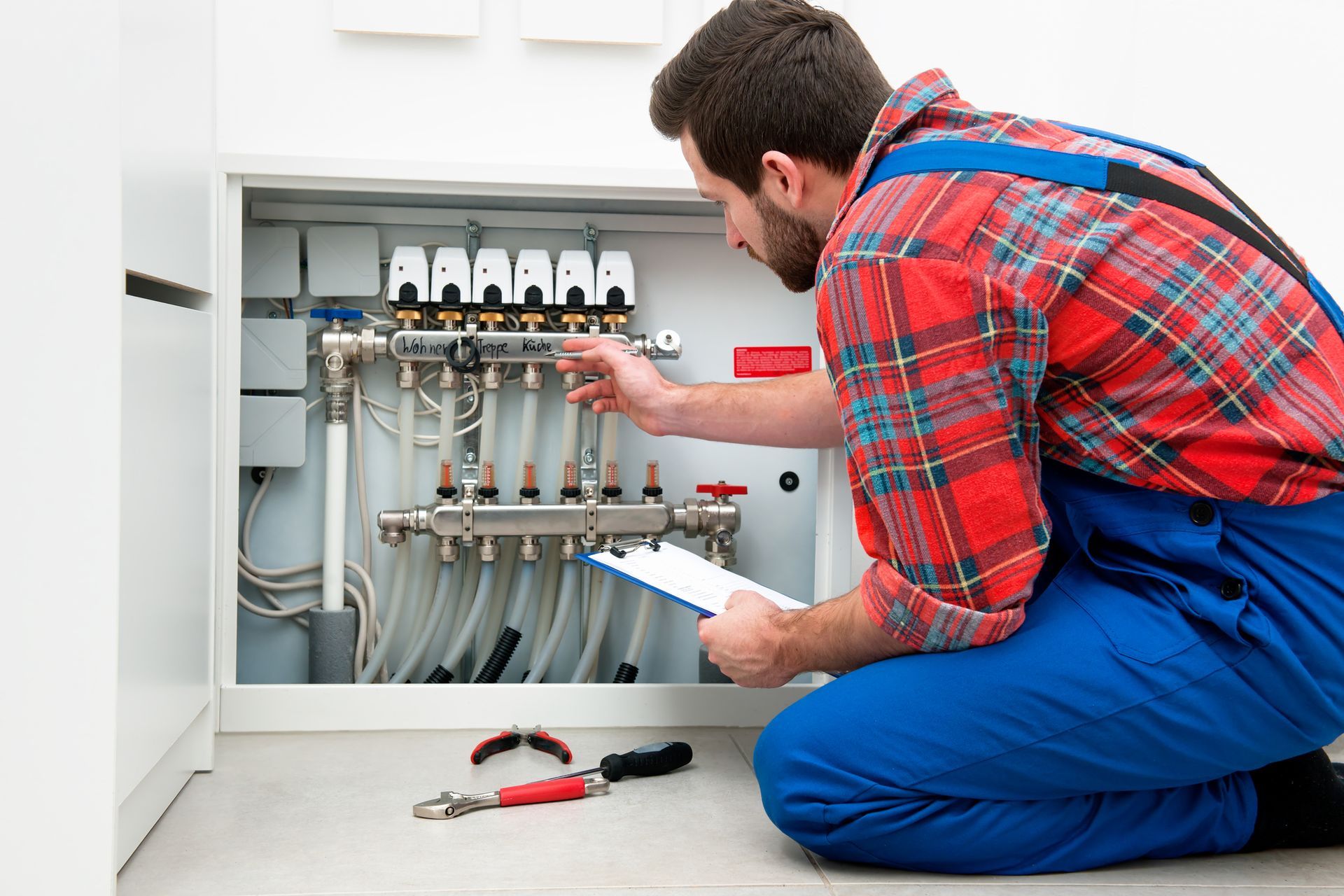 Technician working on underfloor heating manifold, showcasing expert heating repair services.