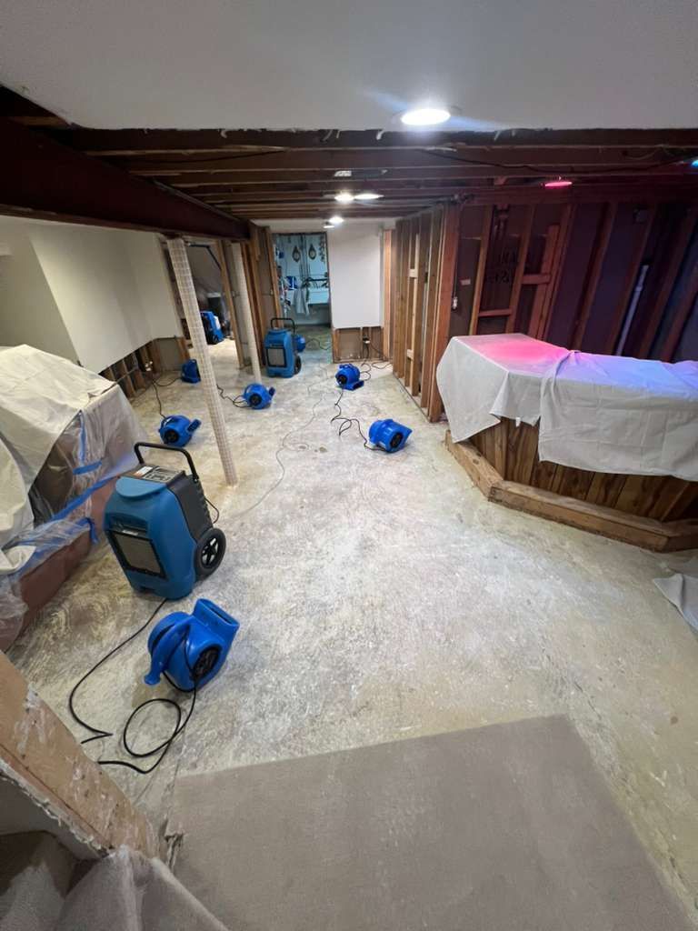 Partially finished basement with exposed beams, tools, and a covered workbench under renovation