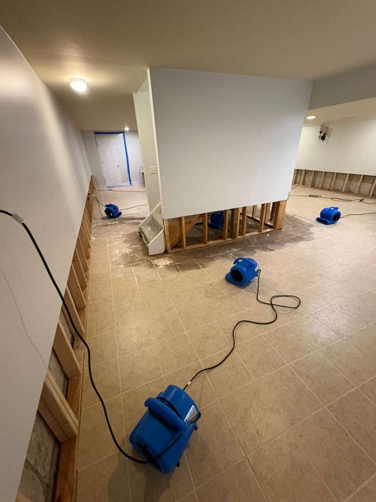 Flooded basement under renovation with blue dehumidifiers and exposed wall studs
