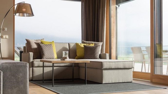 Ein Wohnzimmer mit Couch, Couchtisch und großen Fenstern.