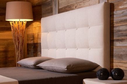 Ein Bett mit zwei Kissen und einem weißem Kopfteil mit Knöpfen.