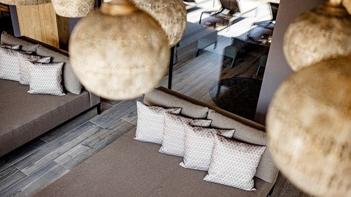 Ein Wohnzimmer mit einem braunen Sofa, Kissen und einer Glasscheibe.